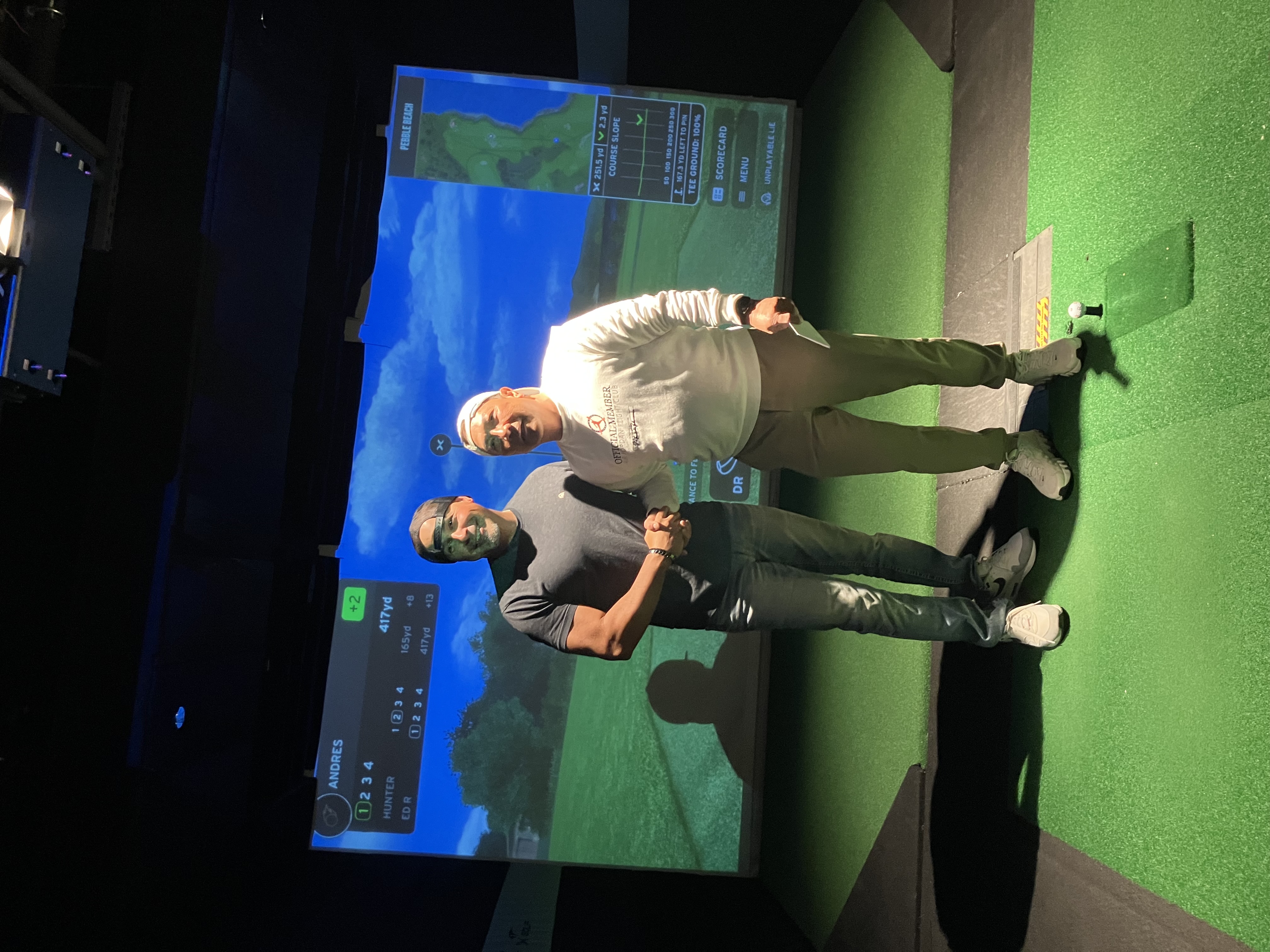 Two competitors shake hands in the golf simulator