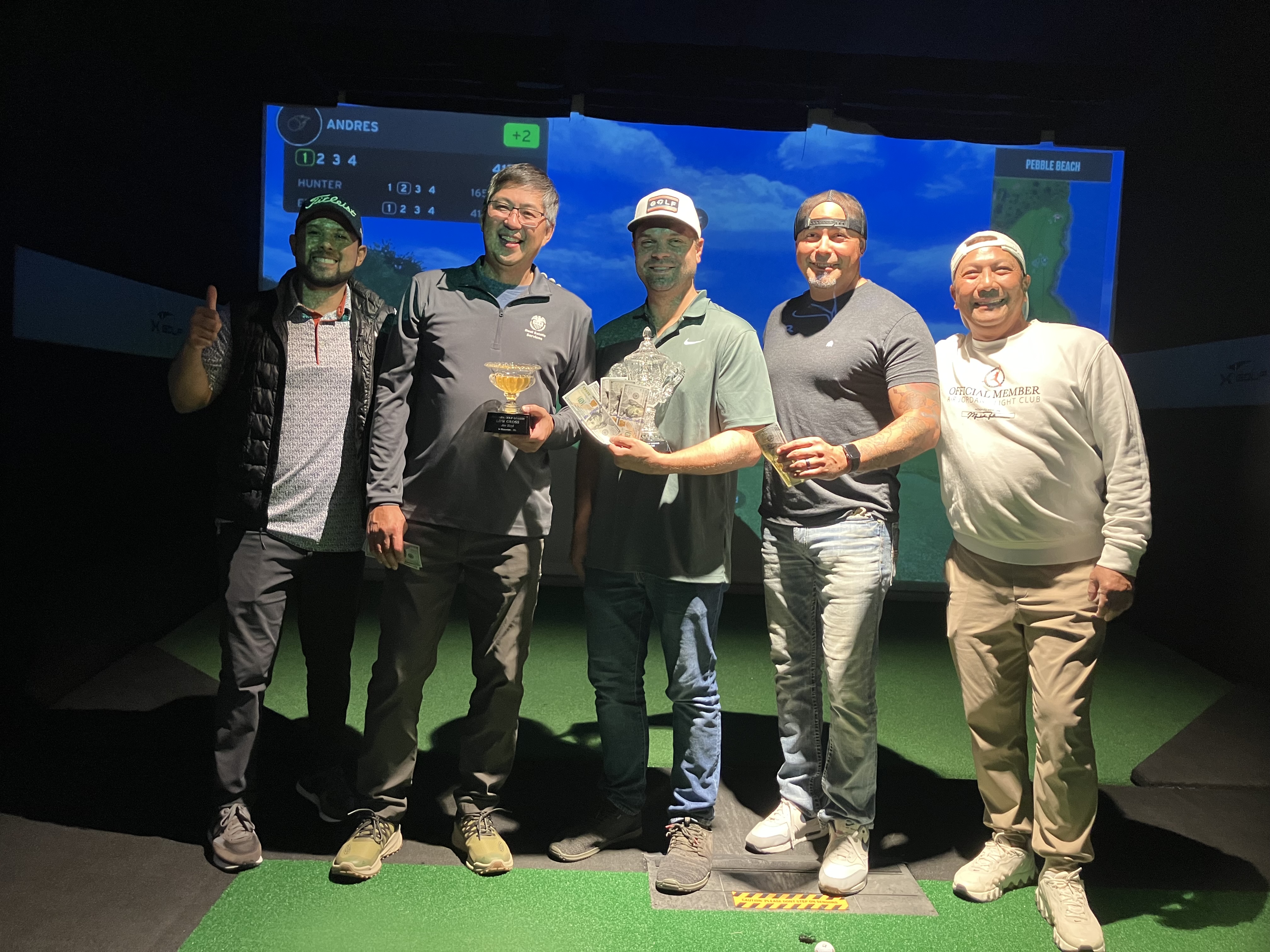 Five members posing with trophies after a simulator tournament