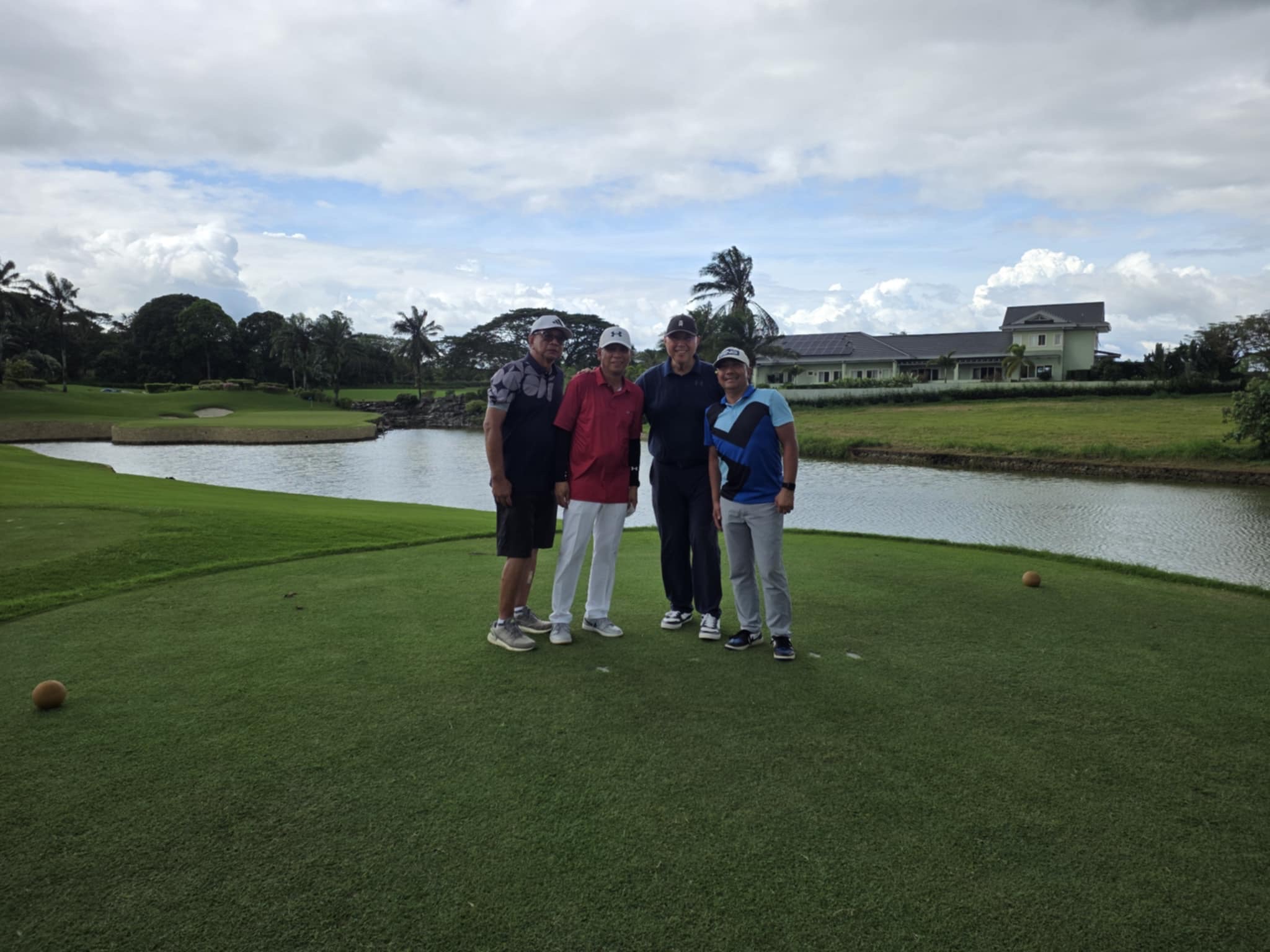 Four golfers on the tee box with scenic lake view